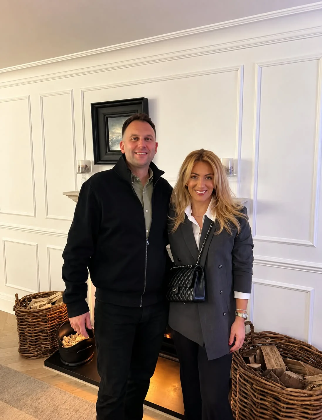 Robert and Kayleigh of Shaw Luxury Real Estate standing together indoors beside a fireplace